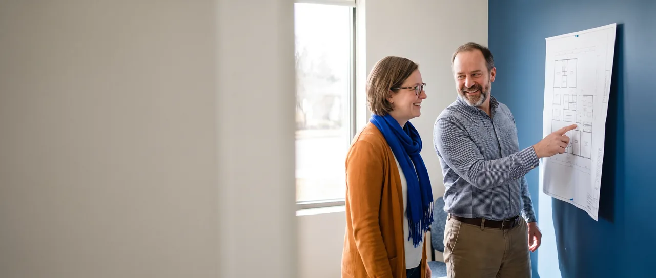 Clinic founder and manager smiling over a plan pinned to the wall