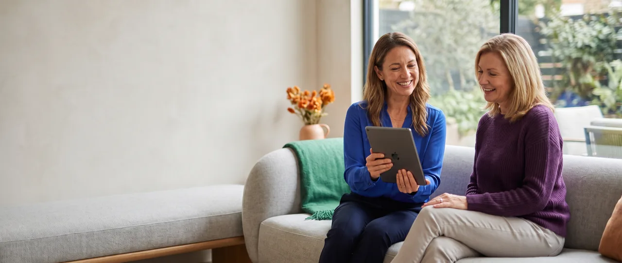 Longevity clinic physician reviewing results with a patient on a sunlit sofa