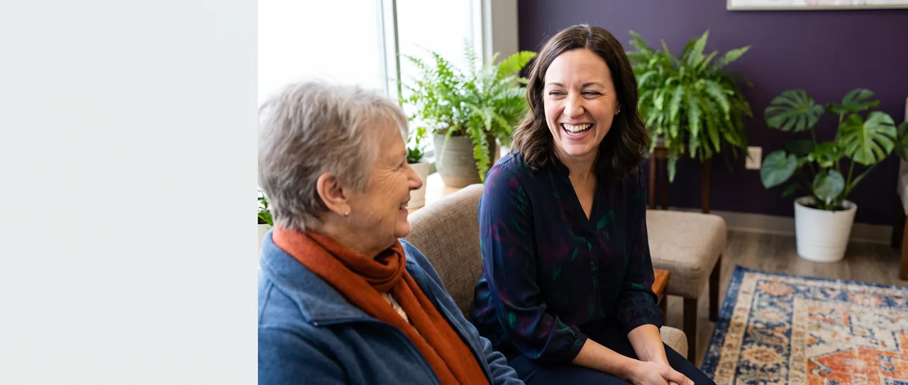 Peptide clinic owner laughing with a patient in a bright waiting room